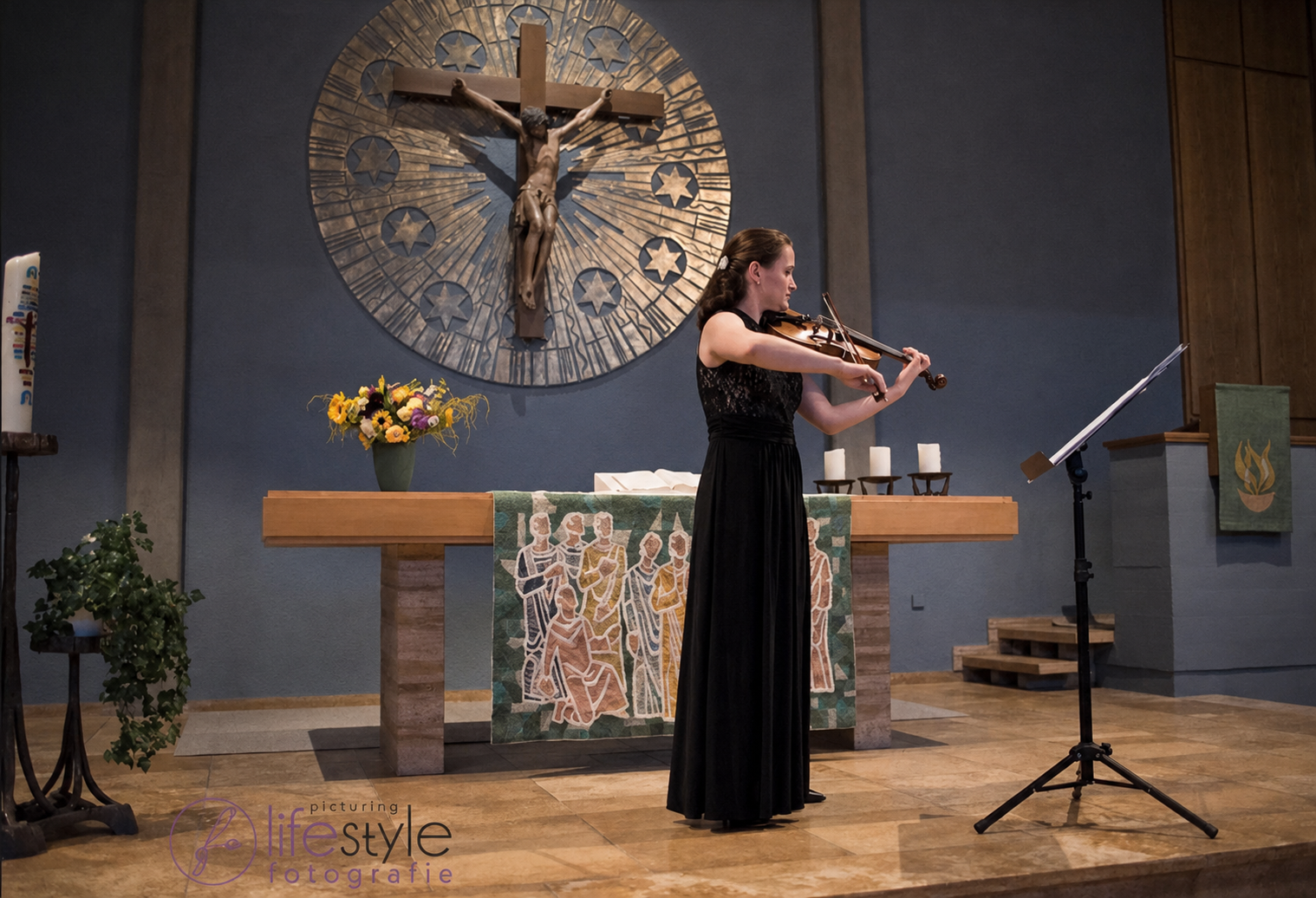 Valeria Gleim spielt Violine vor dem Altar mit Kreuz in der Kirche